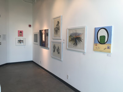 Photo of art pieces hanging on gallery wall.
